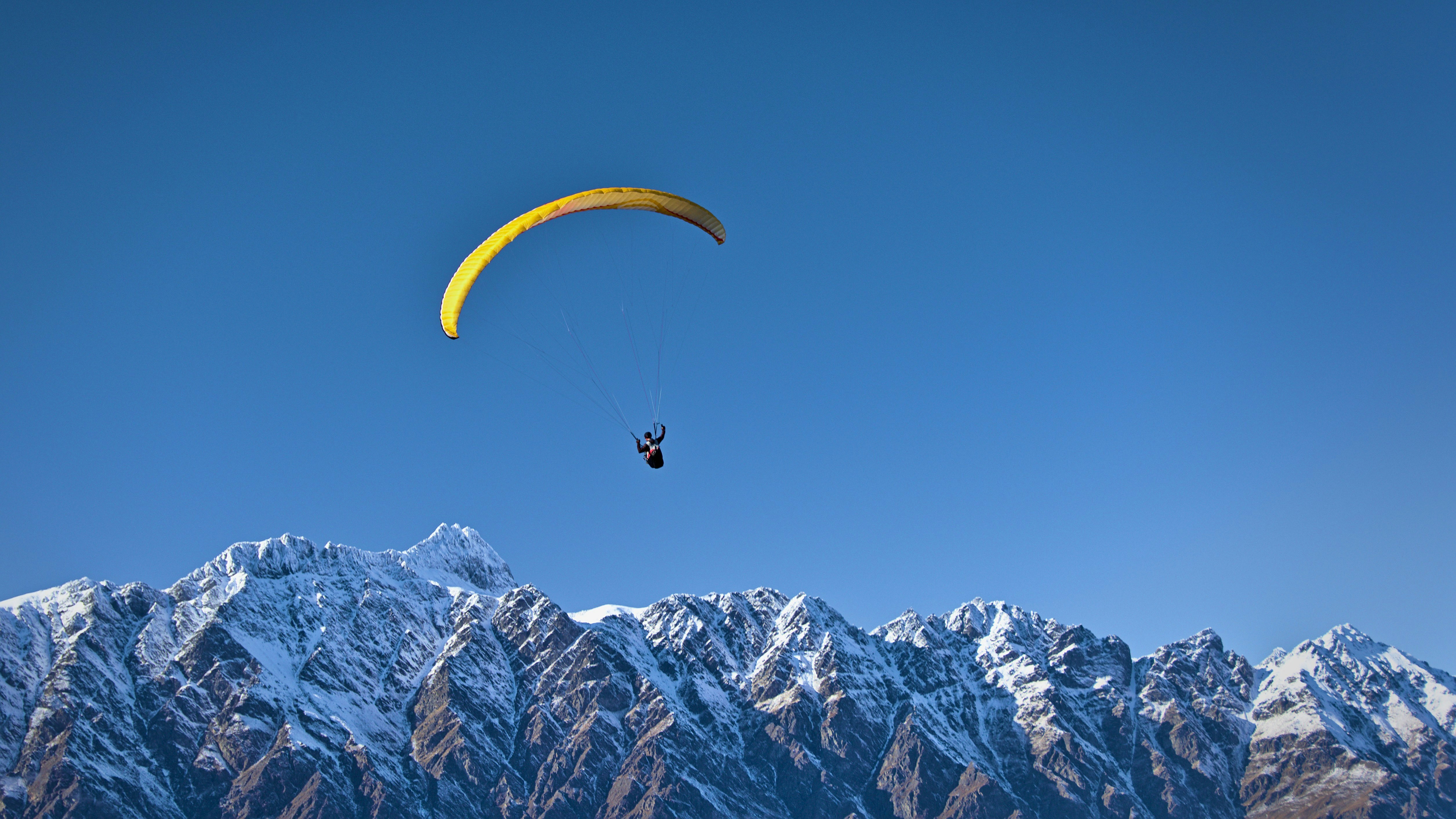 A man doing paragliding in Bir Billing over the Dhauladhar mountains